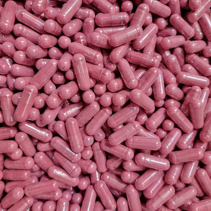 A close-up pile of pink translucent capsules containing organic beetroot powder,  filling the entire frame. 