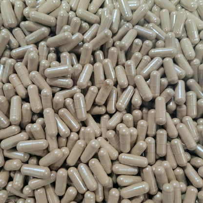 A close-up, top-down view of a dense pile of beige capsules or pills filling the entire frame. 7 mushroom blend capsules vege caps
